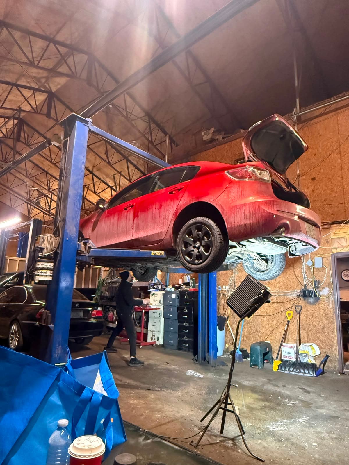 Car raised on a two-post hoist in the Royal Auto Parts workshop with a mechanic working nearby