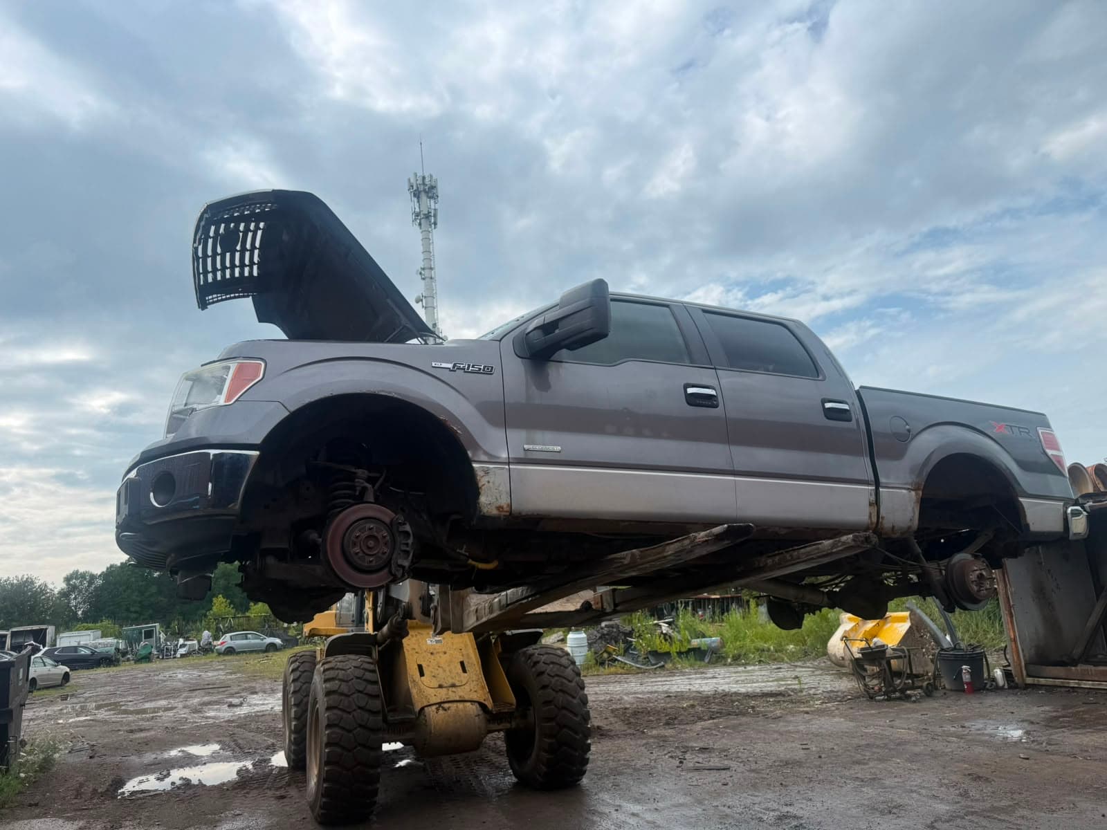 Pickup truck raised on a loader in the Royal Auto Parts yard while its parts are pulled