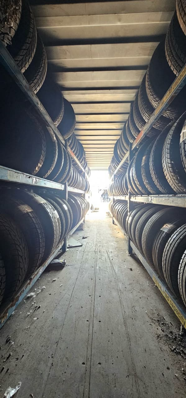 Rows of used tires stacked on steel racks either side of a walkway at Royal Auto Parts